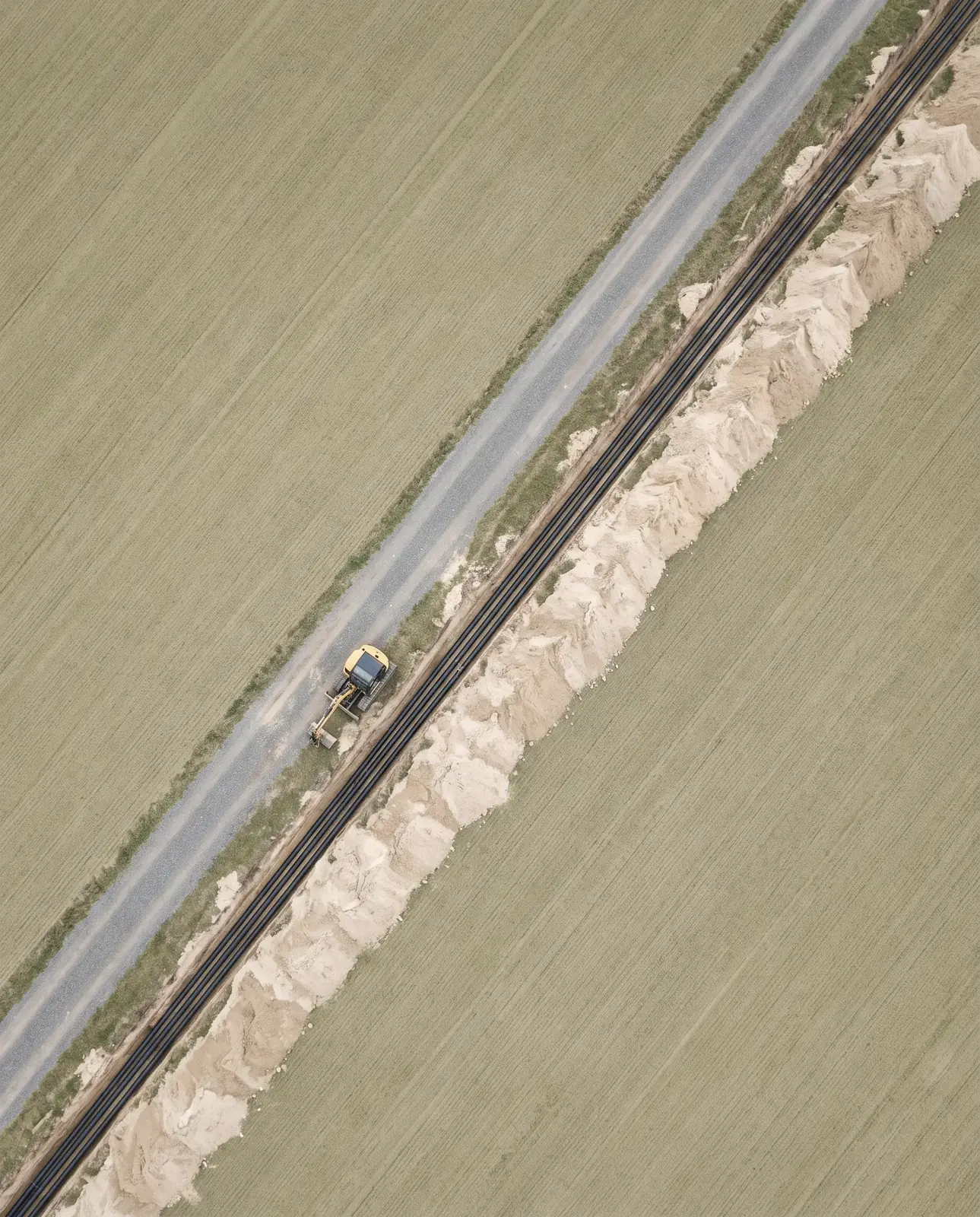 Luftbild einer geraden Kabeltrasse durch ein Feld